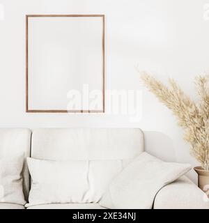 Cornice vuota sopra il divano grigio con pampas asciutte su parete bianca con luce solare, rendering 3d. Foto Stock