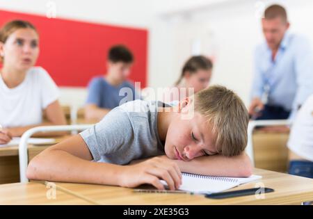 Lo studente stanco si è addormentato sulla scrivania in classe Foto Stock