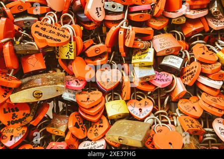 Verona, Italia - Giugno 2022: Sfondo di chiuse a forma di cuore su una parete, simbolo dell'amore per sempre. Foto Stock