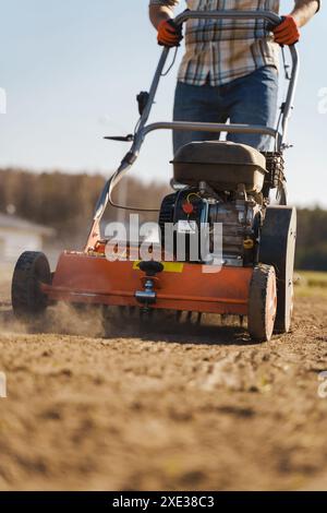 Uomo che usa una macchina aeratrice per la scarificazione e l'aerazione di prati o prati Foto Stock