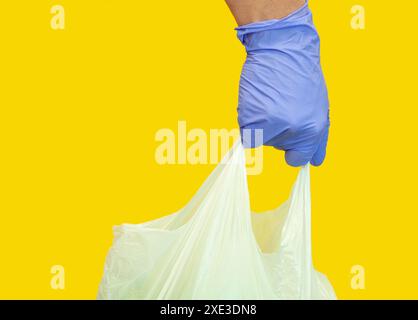 Shopping. mano che tiene la borsa della spesa. Sacchetto di plastica con guanti blu come protezione contro la COVID-19 coro Foto Stock