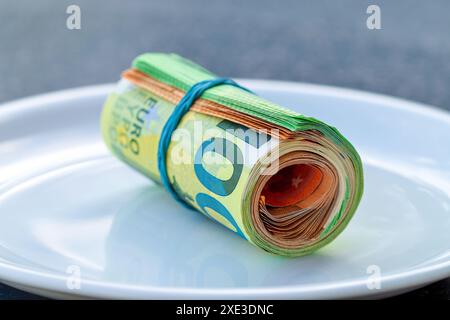 Banconote da 100 e 50 Euro su piastra bianca, attorcigliate nel tubo e legate con una fascia elastica. EUR arrotolato Foto Stock