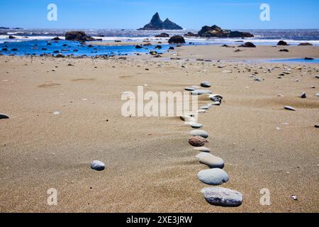 Serene Stone Path sulla costa sabbiosa che conduce all'oceano - prospettiva a basso livello degli occhi Foto Stock