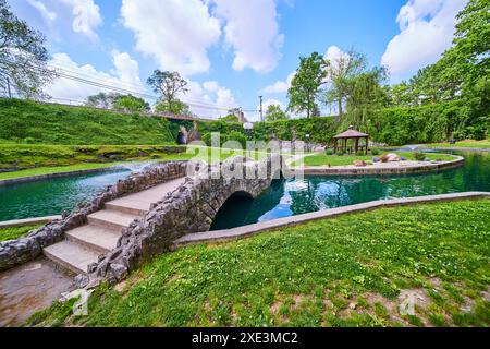 Ponte di pietra e gazebo sullo stagno in un tranquillo ambiente dei giardini sommersi Foto Stock