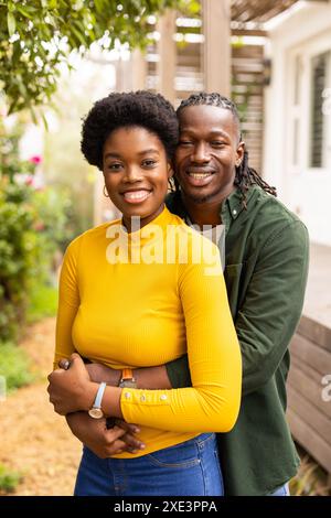 Coppia sorridente che abbraccia l'aria aperta, godendo momenti di qualità insieme a casa Foto Stock