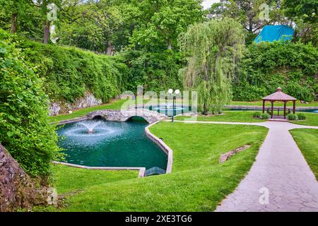 Ponte di pietra sereno e laghetto con fontane nell'Huntington Sunken Gardens Foto Stock