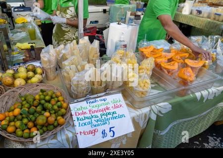 Frutta tropicale tagliata sul tavolo in vendita in un mercato di strada a Honolulu, HI, USA. Foto Stock