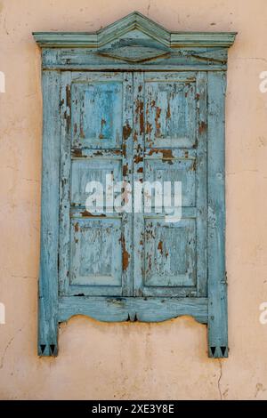 Vecchia finestra in legno con persiane chiuse sulla parete della casa beige Foto Stock