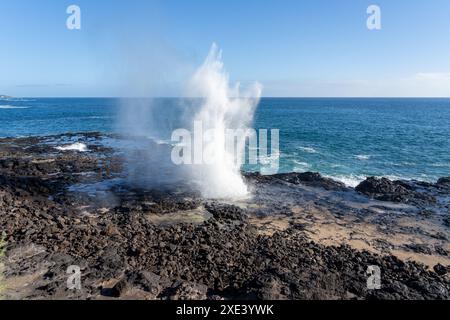 Un blowhole sulla costa sud di Kauai vicino a Poipu, Hawaii, Stati Uniti. Il soffiante spara acqua di mare attraverso il suo tubo di lava naturale fino a 50 metri nell'aria. Foto Stock