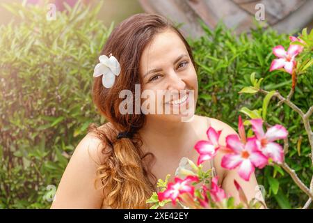 Ritratto di una giovane donna con fiori rosa in vacanza ai tropici Foto Stock