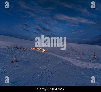 Gli snowboarder (motoslitte per gatti delle nevi) durante l'escursione notturna prima dell'alba fanno un giro in cima alla montagna invernale con freerider e snowboarder. Al Foto Stock