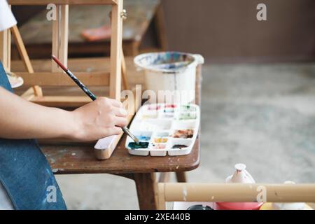 Ispirazione per la creazione: Artista femminile che abbozza e dipinge in officina Foto Stock