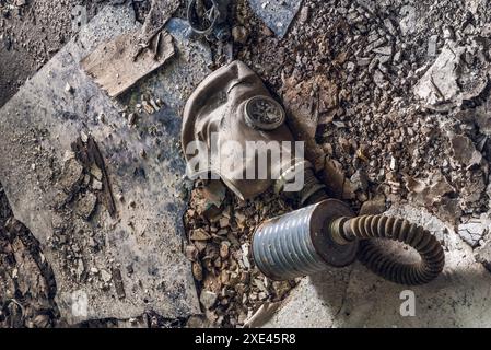 Vecchia maschera antigas sporca adagiata su un terreno industriale disordinato Foto Stock