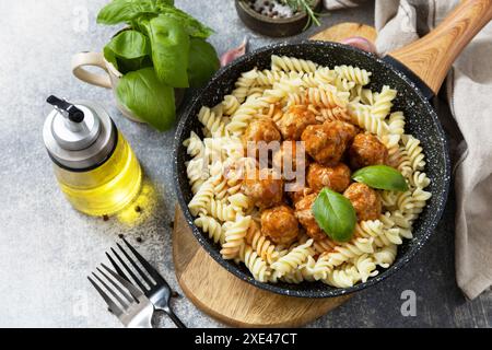 Cucina italiana. Fusilli italiani con polpette di carne in salsa di pomodoro e basilico su sfondo di pietra grigia. Foto Stock