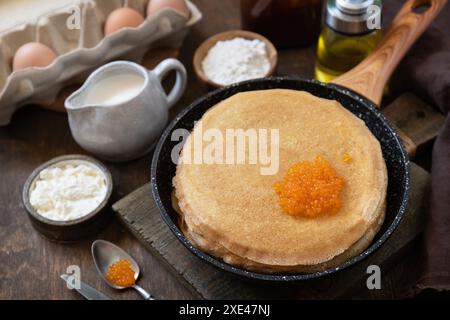 Frittelle di cucina tradizionale russa. Pancake sottili serviti con caviale rosso su un tavolo di legno. Foto Stock