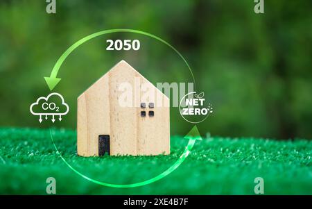 Un modello di casa in legno su sfondo verde e un simbolo di riduzione dell'anidride carbonica, Carbon Credit, Net Zero, concetto di riduzione delle emissioni di CO2, Clean Foto Stock