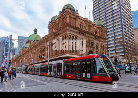 Un veicolo della metropolitana leggera supera lo storico edificio del Department of Lands di Sydney (1892). Sydney, Australia Foto Stock