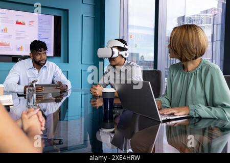 Utilizzando il visore VR, uomo in riunione con i colleghi che discutono del progetto in ufficio Foto Stock