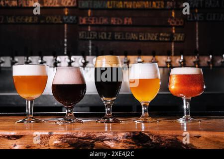 Diversi tipi di birre artigianali in bicchieri sul tavolo all'interno del pub durante il giorno Foto Stock