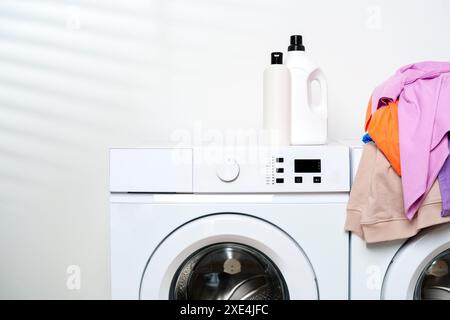 Lavatrici bianche con vestiti colorati in una lavanderia Foto Stock