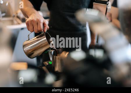 Shot ritagliato di un barista irriconoscibile che produce latte art in una caffetteria specializzata. Un barista professionista che prepara l'espresso. Foto Stock