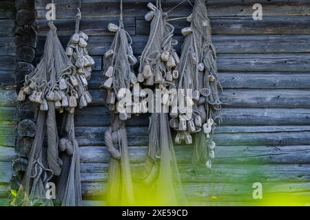 Vecchie reti da pesca d'epoca. Autentiche reti da pesca usate appese su un muro di legno. Decorazioni nautiche decorative. Foto Stock