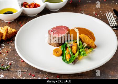 Filet mignon servito con verdure e salse in un raffinato ristorante Foto Stock