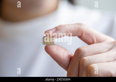 La punta delle dita di una giovane donna che tiene in mano la scheda micro sim Foto Stock