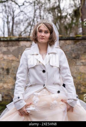 Ritratto di nozze di una giovane e bella sposa moderna con un taglio di capelli corto, vestito con cappotto bianco, soffice abito da sposa Foto Stock