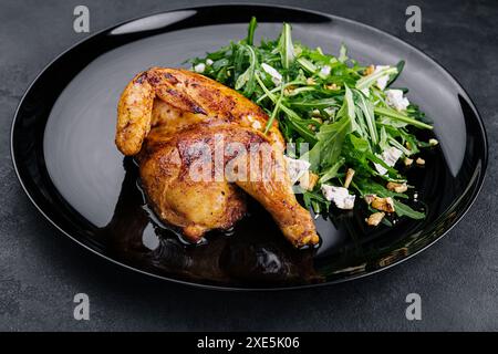 Pollo fritto con insalata di rucola su piatto nero Foto Stock