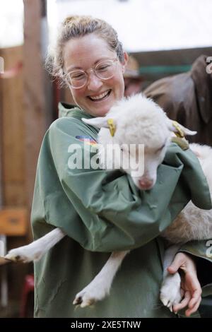 Glueckliche junge Frau mit einem Lamm auf dem Arm, Nordseeinsel Borkum, 18.05.2024. Borkum Deutschland *** giovane donna felice con un agnello tra le braccia, Foto Stock