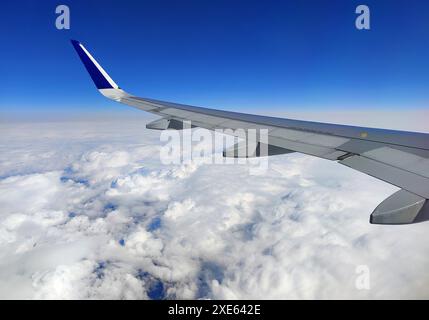 Vista dall'aereo mentre voli su un'ala sopra le nuvole con un cielo blu Foto Stock