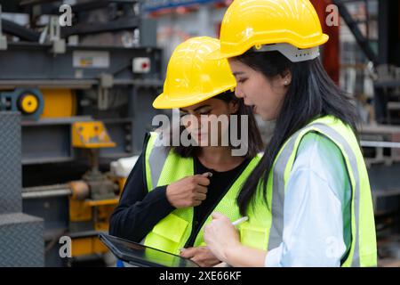 Due ingegneri femminili che lavorano insieme in una fabbrica di lamiere. Questo è un magazzino di trasporto e distribuzione merci. Indù Foto Stock