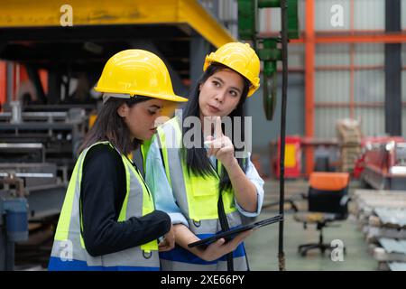 Due ingegneri femminili che lavorano insieme in una fabbrica di lamiere. Questo è un magazzino di trasporto e distribuzione merci. Indù Foto Stock