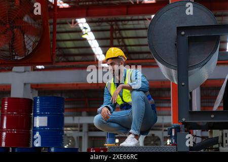 Un giovane lavora in un magazzino che immagazzina rotoli di lamiera. Sedersi rompere e rimuovere il sudore un po' prima di contenerlo Foto Stock