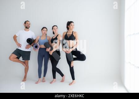 Un gruppo di atleti femminili e maschili si alzò e chiacchierò amichevolmente nello studio prima di iniziare con la lezione di yoga. Foto Stock