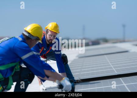 Entrambi i tecnici stanno installando pannelli solari sul tetto del magazzino per trasformare l'energia solare in energia elettrica per noi Foto Stock