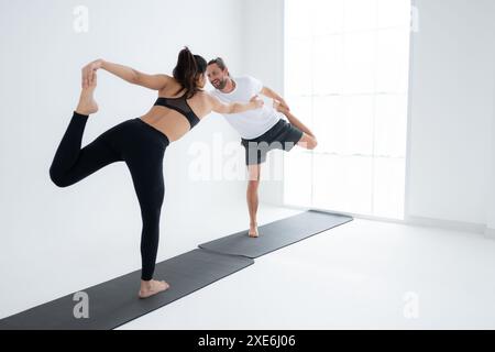 Giovane coppia che pratica yoga in una stanza bianca di studio. Foto Stock