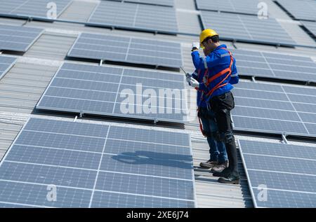 Entrambi i tecnici stanno installando pannelli solari sul tetto del magazzino per trasformare l'energia solare in energia elettrica per noi Foto Stock
