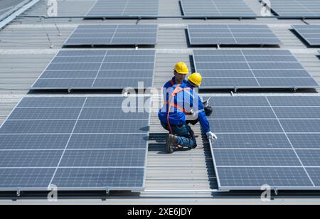 Entrambi i tecnici stanno installando pannelli solari sul tetto del magazzino per trasformare l'energia solare in energia elettrica per noi Foto Stock