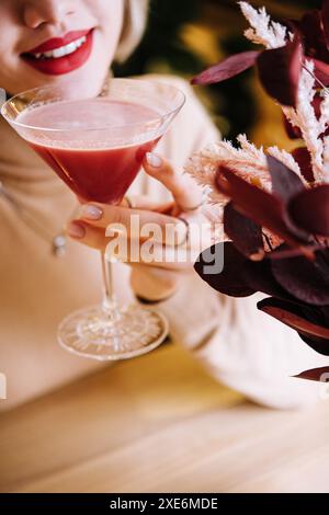 La giovane donna beve un cocktail rosso con fragole Foto Stock