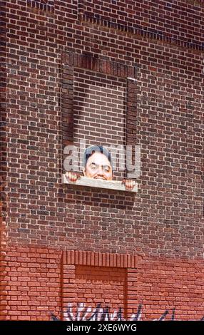 NYC Chinatown: Simpatici coetanei da una finestra in mattoni al 72-80 di Henry Street, una struttura del Dipartimento di Sanitation sotto il ponte di Manhattan. Foto Stock