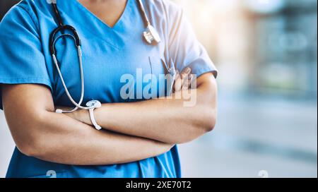 Assistenza sanitaria, sicuro di sé e mani di infermiere con stetoscopio per la cura, il servizio e professionale in ospedale. Cardiologia, braccia incrociate e donna nell'atrio Foto Stock