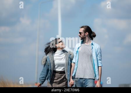 Giovani coppie che si rilassano vicino alla turbina eolica sul lago Foto Stock