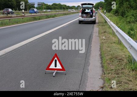 Un'auto in avaria si ferma sull'autostrada con un triangolo di pericolo e pericolo dietro di essa Foto Stock