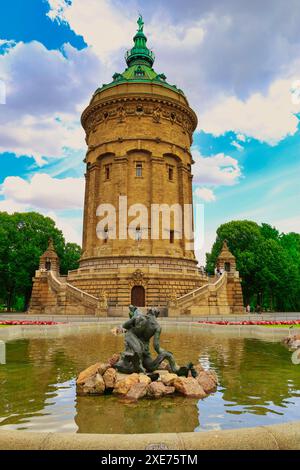 La torre dell'acqua di Mannheim, Germania, con grandi alberi sullo sfondo con fiori da giardino Foto Stock