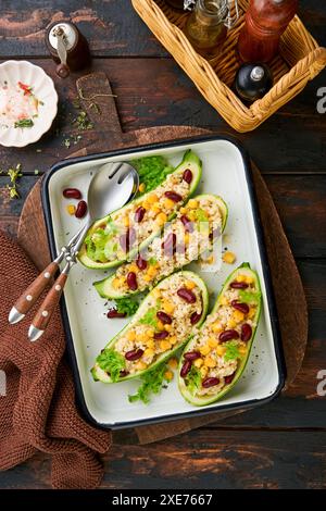 Zucchine ripiene di petitim, fagioli rossi, mais con basilico e salsa cotte su un vecchio sfondo di legno scuro. Vista dall'alto. Foto Stock