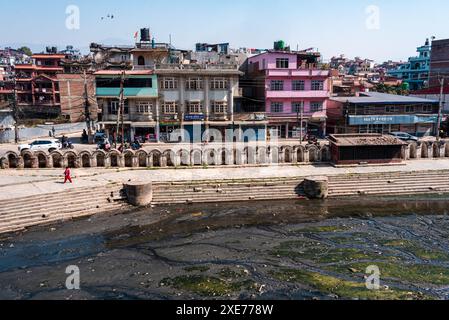 Ammira le acque inquinate del sacro fiume Bagmati di fronte alle tipiche case nepalesi, Pashupatinath, Kathmandu, Nepal, Asia Foto Stock