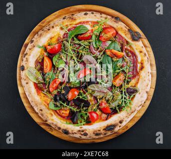 Pizza dall'alto con salame, pomodori e basilico con rucola Foto Stock