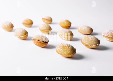 Biscotti a forma di noce con crema su bianco Foto Stock